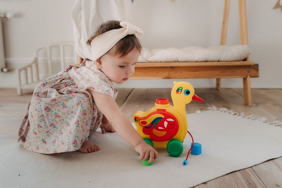 A toddler playing with a pull-along duck