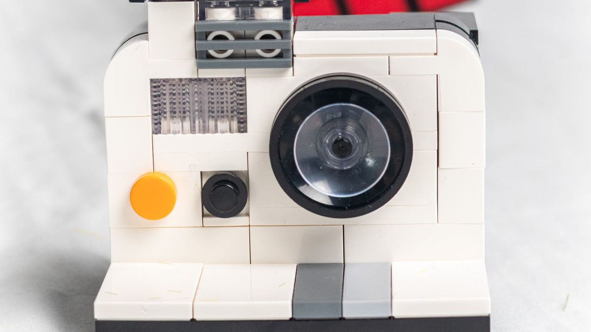 Brick-built vintage instant camera model on a marble surface