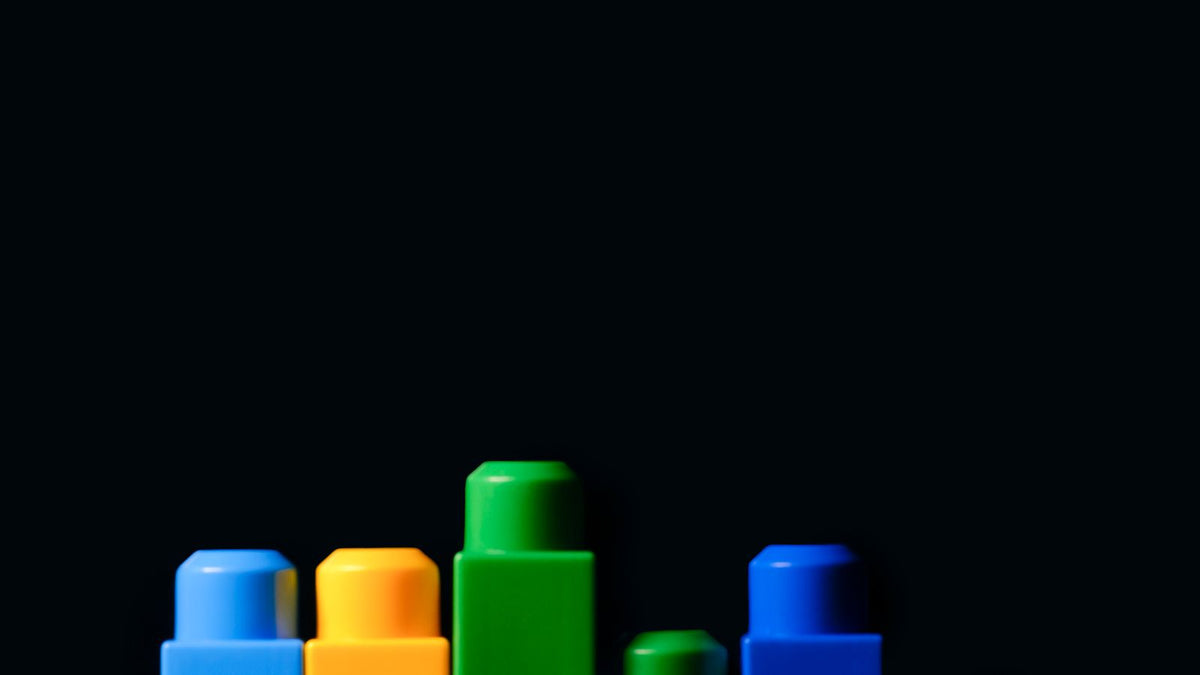 Large plastic toy blocks stacked in rising heights on a black background