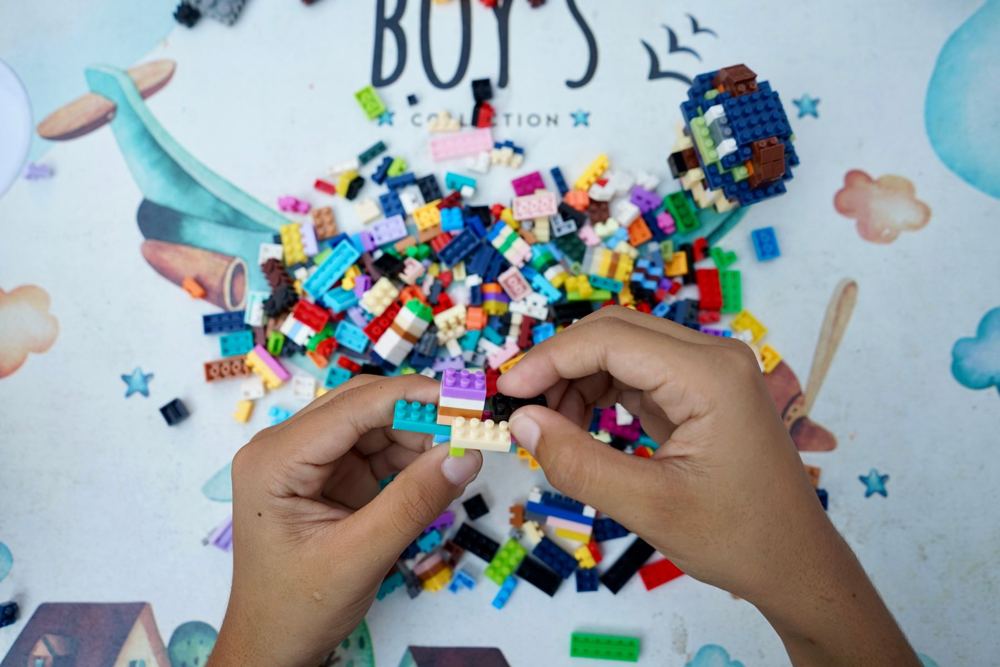 Hands building with small colorful bricks on a play mat