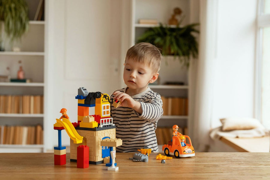 A toddler building with large bricks at a table