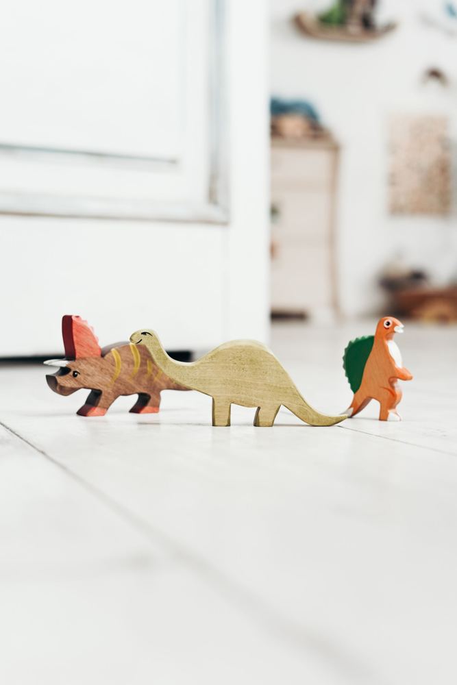Wooden dinosaur toys on a white floor